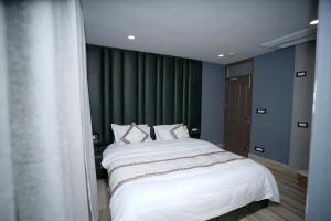 シュリーナガルにあるHotel Asian Comfortの白いシーツが敷かれた大きなベッドのある寝室