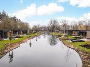 アペルドールンにあるVeluwepark de Bosgraafのいくつかの建物の前の川