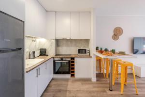 una cucina con armadi bianchi e sgabelli gialli da bar di Yellow Breeze Apartament a Viana do Castelo
