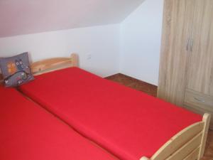 a red bed with a red blanket on top of it at Apartmán u Růženky in Veselí nad Lužnicí