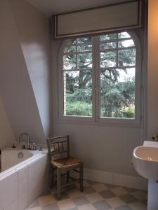 a bathroom with a tub and a chair and a window at House facing Roland Garros stadium - 5 bedrooms in Boulogne-Billancourt