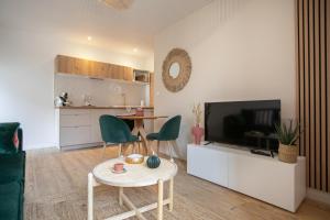 a living room with a television and a table and chairs at Bel appartement neuf en plein centre in Brantôme