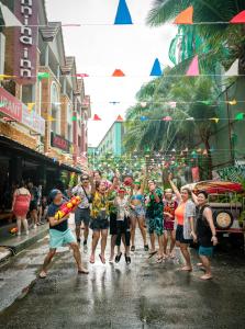 a group of people walking down a street in the rain at EBS Hostel Phuket in Ban Karon