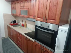 a kitchen with wooden cabinets and a stove top oven at Green Peace Apartman 1 in Kragujevac