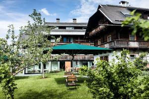 a large building with a green umbrella in the yard at Biohotel Gralhof in Weissensee