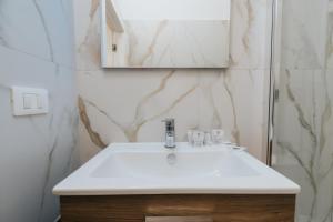 ein Badezimmer mit einem weißen Waschbecken und einem Spiegel in der Unterkunft Desire Home in Bari