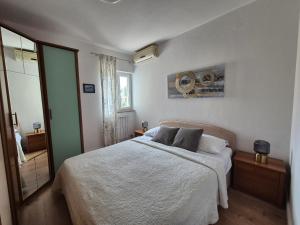 a bedroom with a white bed and a mirror at Apartment Danijela No. 2 in Novalja