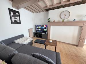 a living room with a couch and a clock on the wall at Maison 2ch - Netflix - Fléchettes - Hyper centre in Douai