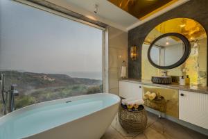 HarnaiSaffronStays Nautica - 5BR hilltop villa with rooftop pool, sea views & modern interiors surrounded by greenery的带浴缸和大窗户的浴室