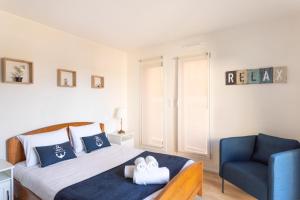 a bedroom with a bed and a blue chair at L'Abri Côtier d'Argäe - Terrasse vue mer in Erquy