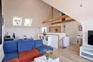 a living room with a blue couch and a kitchen at L'Abri Côtier d'Argäe - Terrasse vue mer in Erquy