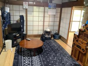 a living room with a wooden table and a coffee table at ゲストハウスやごろう in Iizuka