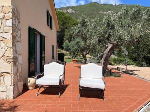 deux chaises blanches posées sur un patio en briques dans l'établissement L'Hermitage- Monte Argentario, à Monte Argentario