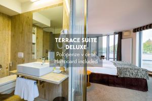 a bathroom with a sink and a bed and a mirror at Amenity Hotel & Resort Lipno in Lipno nad Vltavou