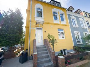 a yellow house with a white door and stairs at ImmoStay M#Apartments Waterfront - WiFi & Parking in Bremen