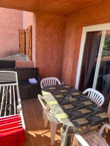 einen Tisch und Stühle auf einer Veranda mit einem Tisch und Stühlen in der Unterkunft LES BULLES DE MONA - Marina Corse - 2 ch - Clim - Terrasse-pieds dans leau-plage in Ghisonaccia