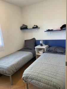 2 Betten in einem Zimmer mit 2 Regalen an der Wand in der Unterkunft LES BULLES DE MONA - Marina Corse - 2 ch - Clim - Terrasse-pieds dans leau-plage in Ghisonaccia