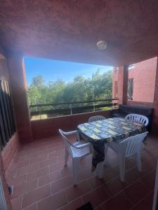 ein Balkon mit Tisch und Stühlen und einem Fenster in der Unterkunft LES BULLES DE MONA - Marina Corse - 2 ch - Clim - Terrasse-pieds dans leau-plage in Ghisonaccia