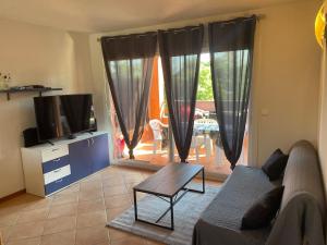 ein Wohnzimmer mit Sofa und Fernseher in der Unterkunft LES BULLES DE MONA - Marina Corse - 2 ch - Clim - Terrasse-pieds dans leau-plage in Ghisonaccia + 26 Fotos