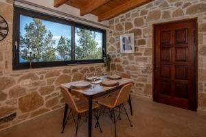 a stone room with a table with chairs and a window at Coral Summer Lux Cottage in Argassi
