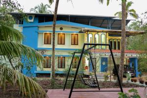 a blue and yellow house with a swing at Evara Homestay in Mararikulam
