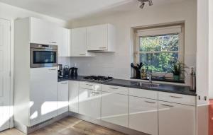 a kitchen with white cabinets and a sink and a window at Bodelaeke-Grote Punter Luxe in Giethoorn