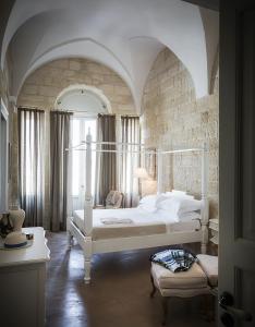1 dormitorio con 2 camas blancas y pared de ladrillo en Don Totu - Dimora Storica, en San Cassiano