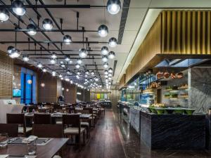 太原太原富力铂尔曼大酒店的有桌椅和灯的餐厅