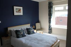 a bedroom with a bed with blue walls and a window at The Old Buoy Inn in Seahouses