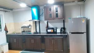 a kitchen with brown cabinets and a refrigerator at Tanakorn House in Thong Nai Pan Yai