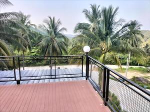 a balcony with a view of the water and palm trees at Tanakorn House in Thong Nai Pan Yai