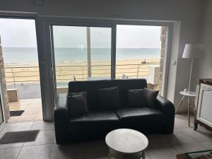 un soggiorno con divano e vista sulla spiaggia di La terrasse de l'océan a Pléneuf-Val-André