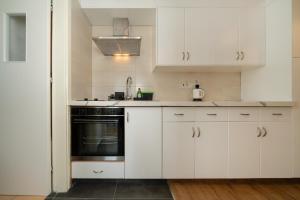 een keuken met witte kasten en een zwarte oven bij 1 bedroom flat in city center in Nicosia