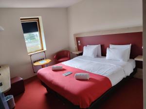 a hotel room with a large bed with a red blanket at Kyriad Laon in Laon