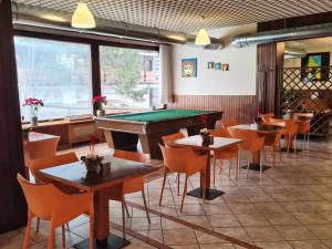 a pool table in a restaurant with tables and chairs at Excelsior Hotel Cimone LowCost in San Martino di Castrozza