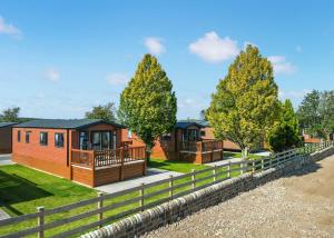 a row of modular homes with trees and a fence at Wild Rose Holiday Park in Colby