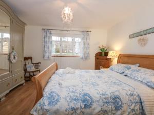 ein Schlafzimmer mit einem blauen und weißen Bett und einem Kronleuchter in der Unterkunft Bramley Cottage in Beaumaris