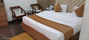 a bedroom with a large bed and two chairs at hotel the royal jewel in Hisār