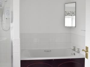 ein weißes Bad mit einer Badewanne und einem Spiegel in der Unterkunft Rudda Farm Cottage - Uk2492 in Staintondale