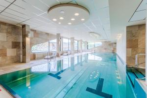 a swimming pool with blue water in a building at Amenity Hotel & Resort Lipno in Lipno nad Vltavou