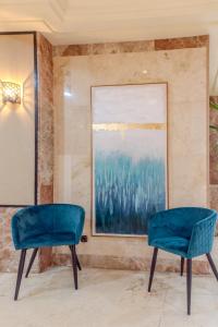 two blue chairs in a room with a painting at Hotel Aeropuerto Sur in San Isidro