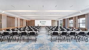 武汉武汉空港逸衡酒店的配有桌椅和屏幕的会议室