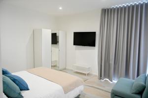 ein weißes Schlafzimmer mit Bett und Fernseher in der Unterkunft Crazi Suites in Nola
