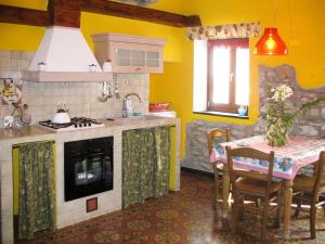 a kitchen with a table and a kitchen with yellow walls at Apartment Limone by Interhome in Dolcedo