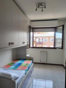 Un dormitorio pequeño con una cama y una ventana. en Trilocale in Via delle Azzorre, en Lido di Ostia