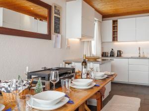 uma cozinha com uma mesa de madeira com pratos e copos de vinho em Apartment Les Cimes by Interhome em Les Crosets