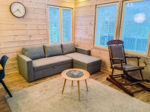 ein Wohnzimmer mit einem Sofa, einem Stuhl und einer Uhr in der Unterkunft Holiday Home Pikku-pölly by Interhome in Vuokatti
