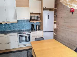 eine Küche mit weißen Schränken, einem Tisch und einem Kühlschrank in der Unterkunft Holiday Home Pikku-pölly by Interhome in Vuokatti + 22 Fotos