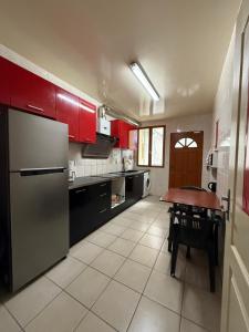 a kitchen with red cabinets and a table in it at Face à la gare - Chambre 2 in Roanne