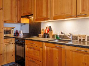シャンペリーにあるApartment Neige et Soleil by Interhomeのキッチン(木製キャビネット、ステンレス製のシンク付)